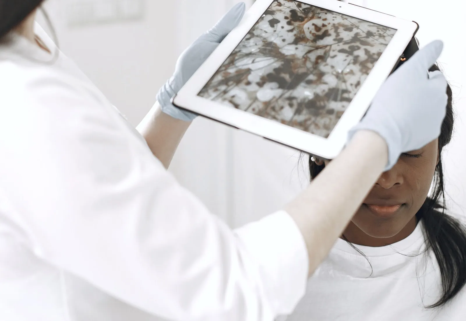 A clinician reviewing magnified skin on a tablet screen during an assessment.