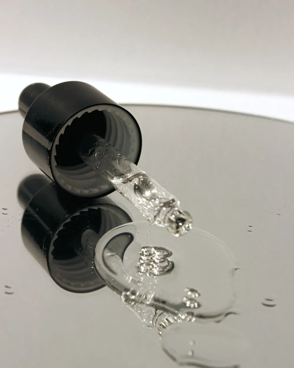 A glass pipette drawing solution from a bottle.