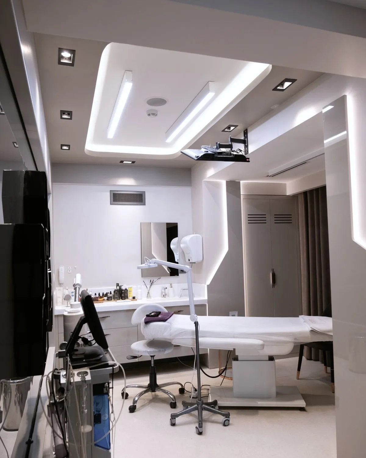 Dr Ayesha Karim in the Aster consulting room, seated beside a window with a dermatoscope on the desk in front of her.