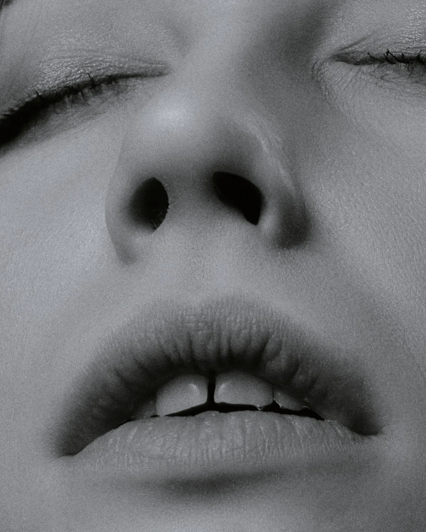 A face at rest, eyes closed, in black and white.